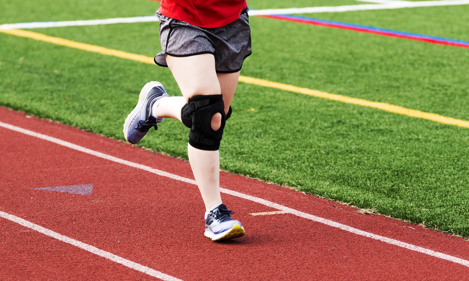 a person running on a track with a knee brace on